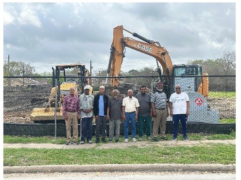 Al-Amin community members standing together in front of an excavator at the two-acre site on Blue Ridge Road, Houston.